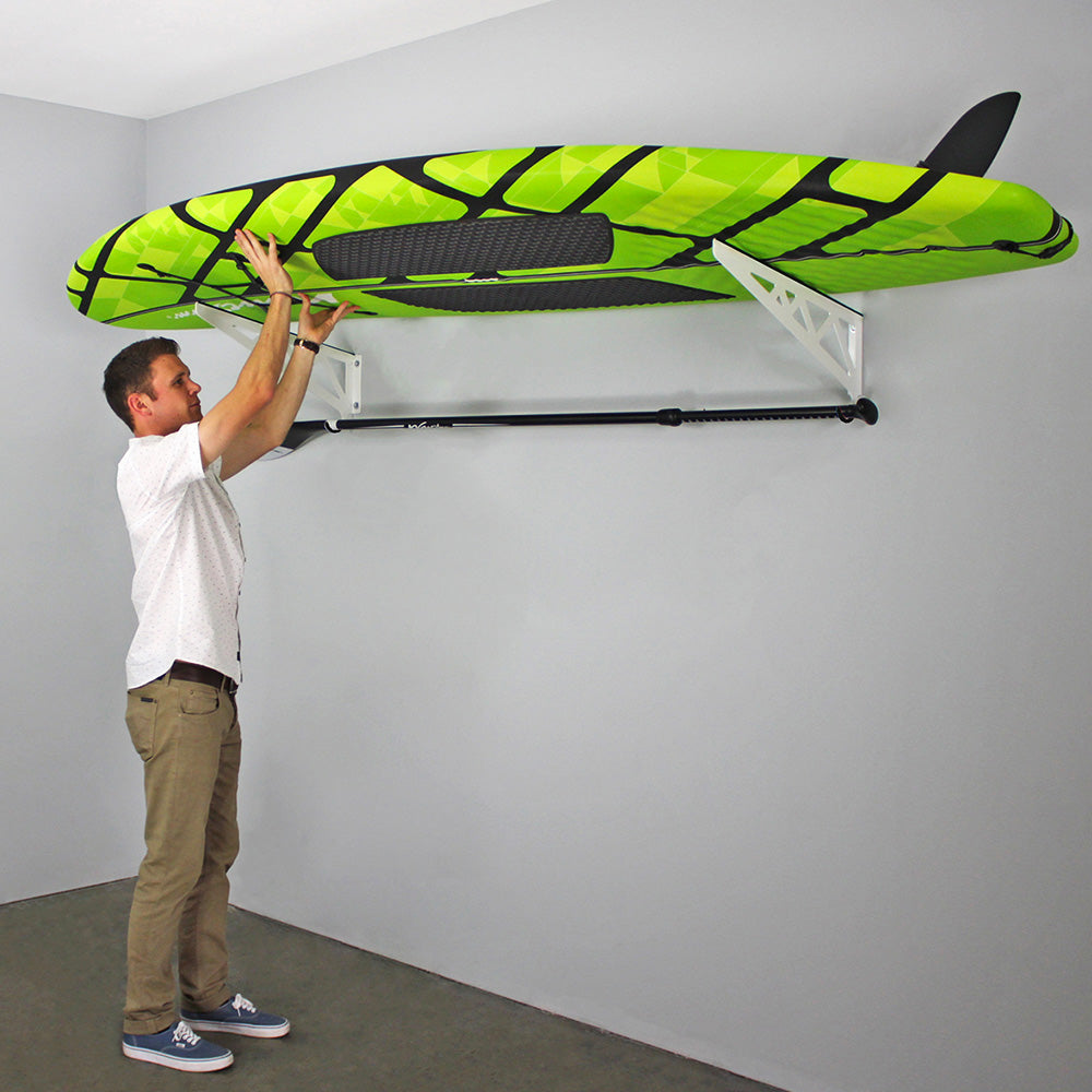 man setting paddle board on rack